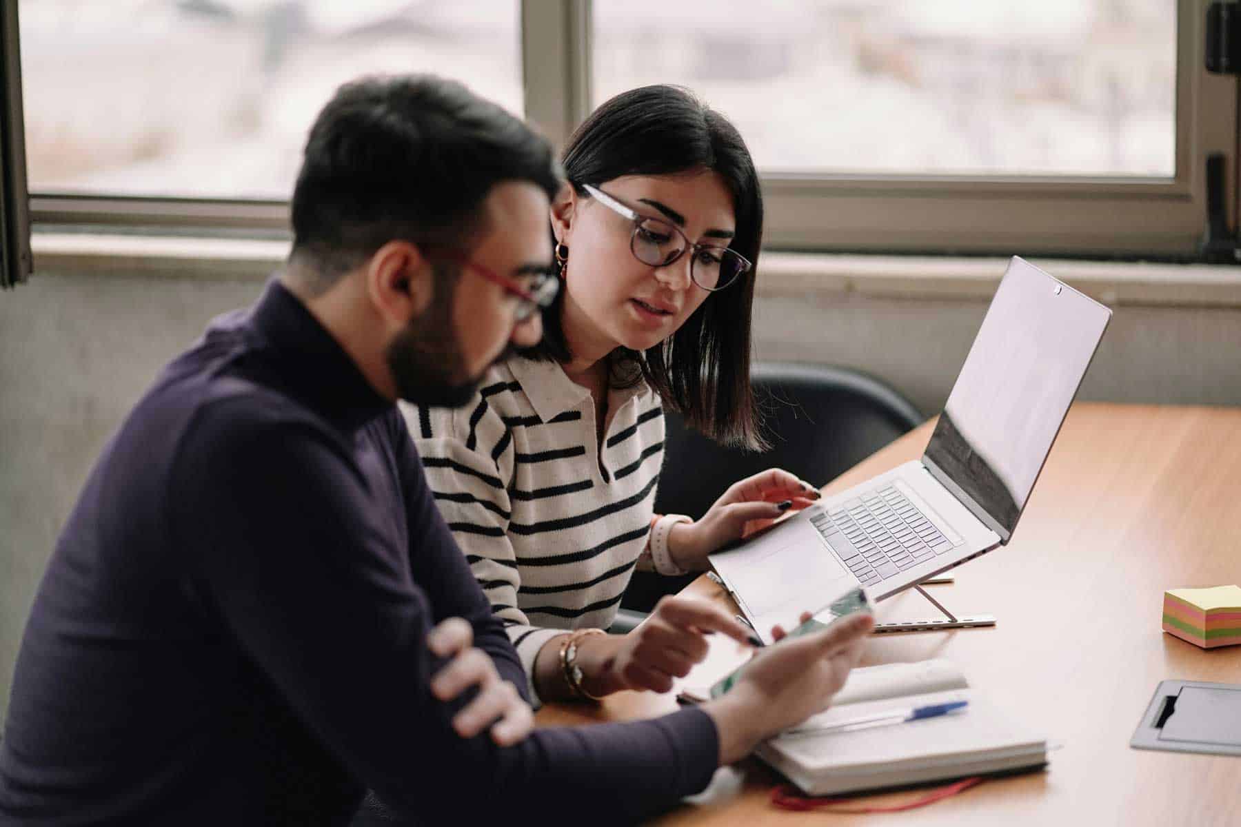 Two researchers collaborating ideas seated side by side in an office scenario